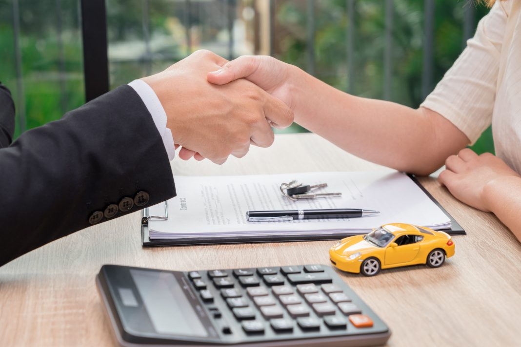 Sale man or businessman shaking hands with female after car loan A handshake signifying a completed loan deal