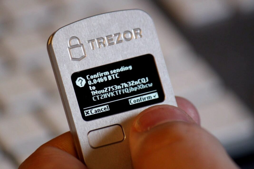 Person using a Trezor One hardware wallet to confirm the sending of some bitcoin
