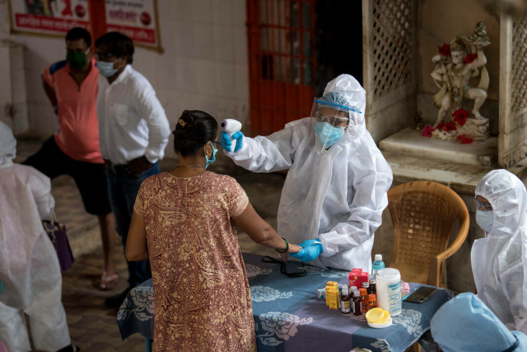 Medical staff wearing protective gear monitor people's body temperature during COVID-19