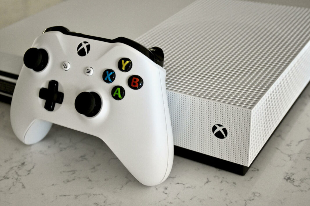 A White Xbox One S console and controller on a carrera marble surface