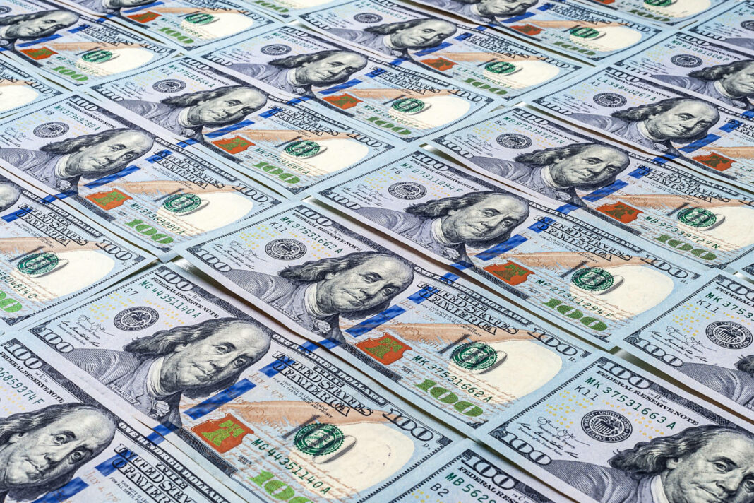 One hundred US dollar bills spread on a table