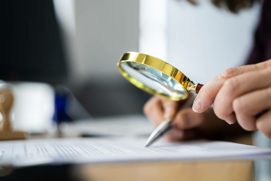 Auditor looking through magnifying glass