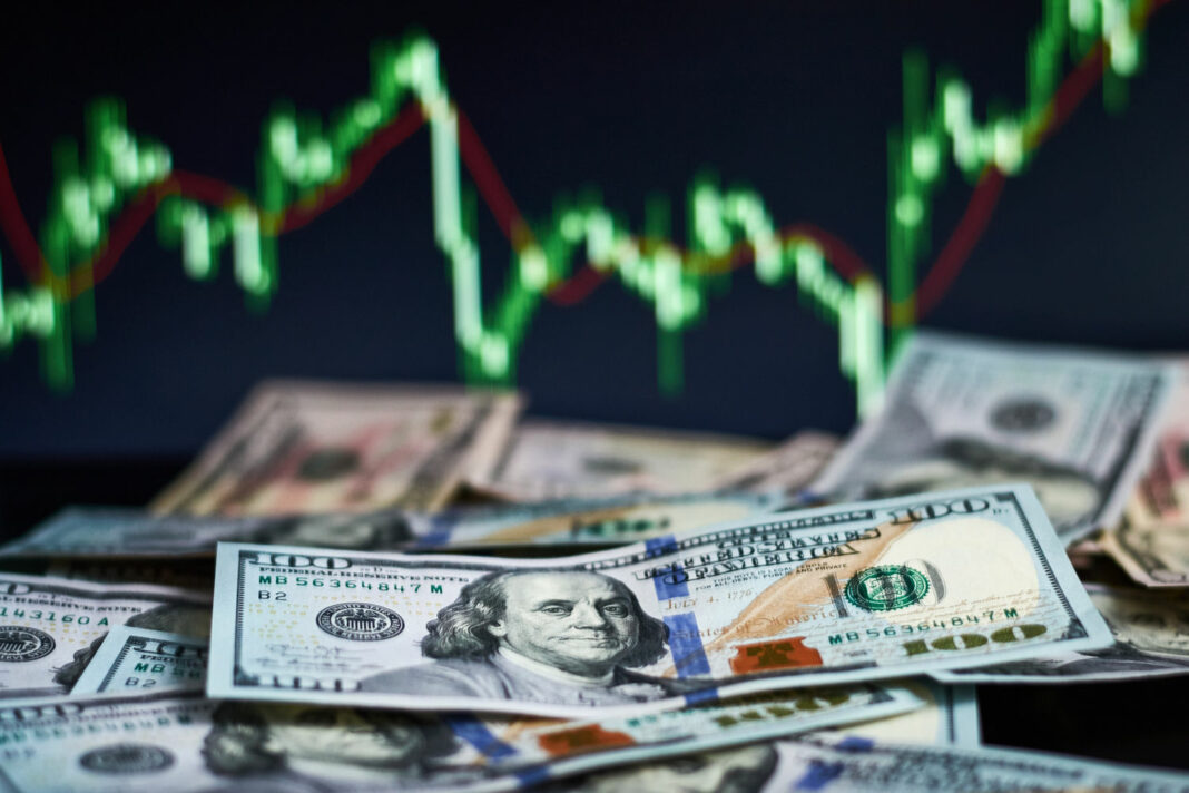 US dollar bills on background with dynamics of exchange rates.